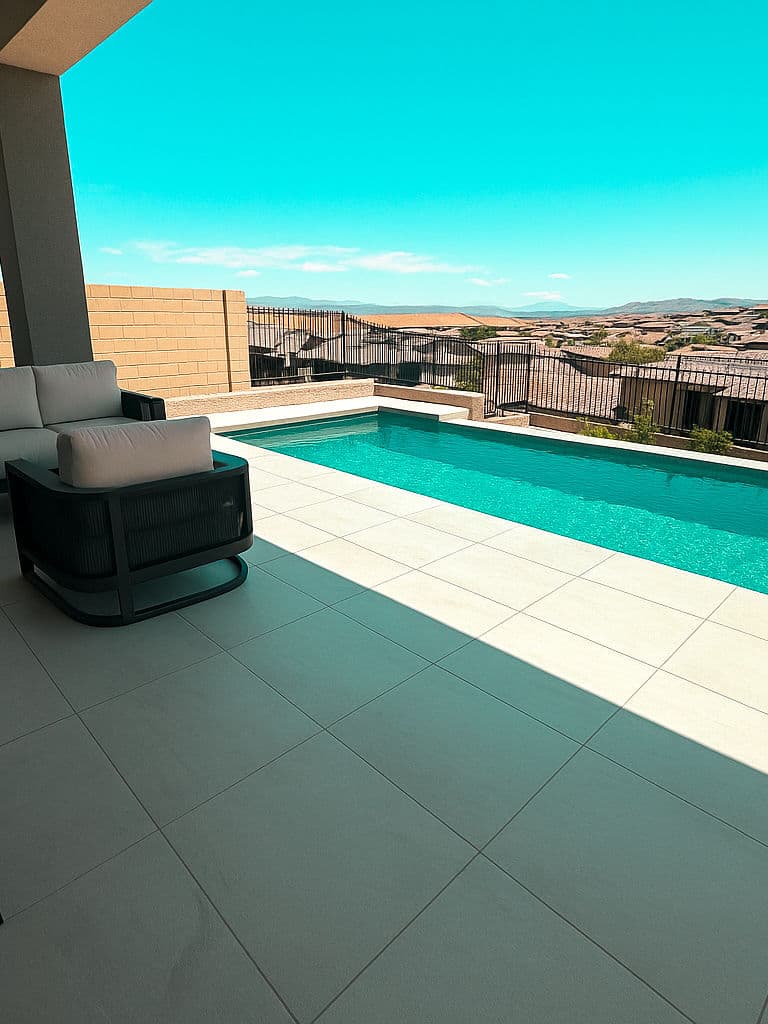 Modern patio with lounge chair overlooking a sparkling pool and scenic landscape.