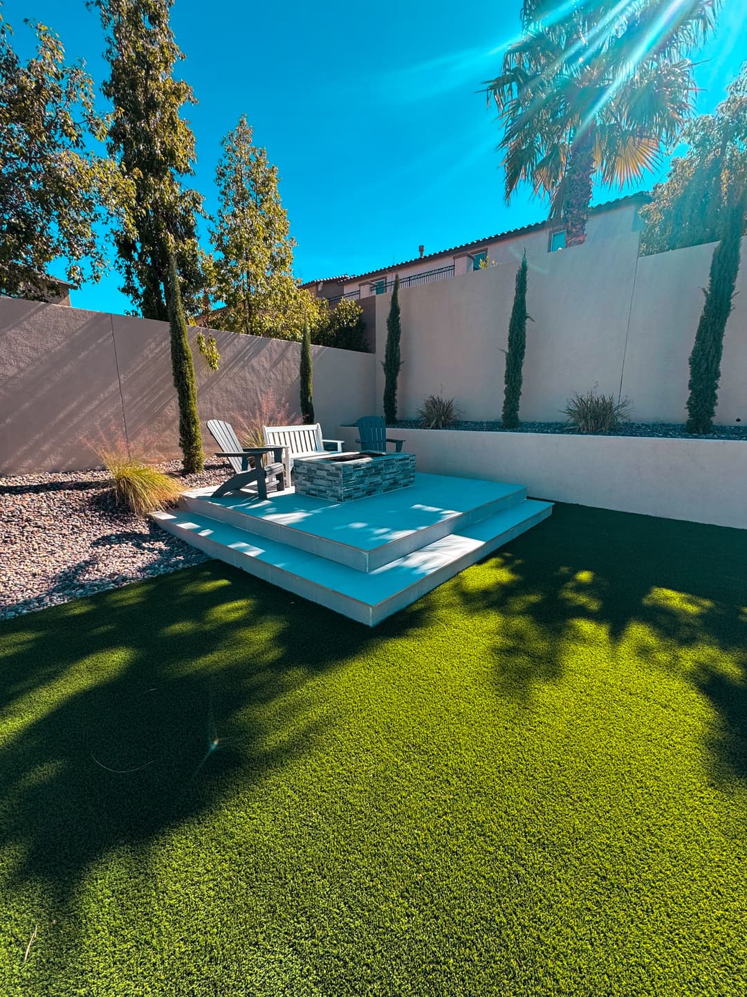 Modern backyard featuring artificial grass, stylish seating area, and sunlight-drenched landscaping.