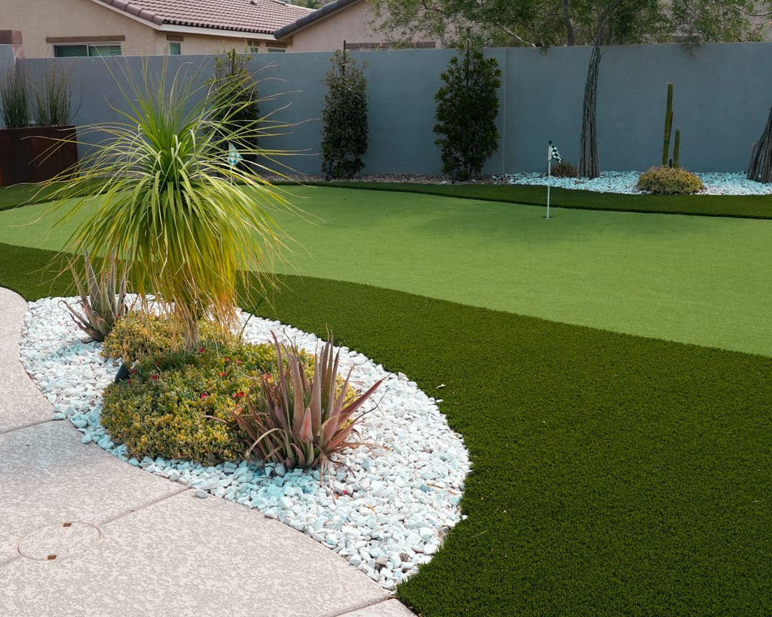 Lush green lawn with ornamental plants and decorative stones in a residential garden.