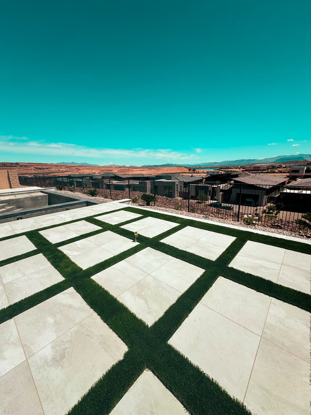 Modern patio design with green grass lines, overlooking a scenic desert landscape.