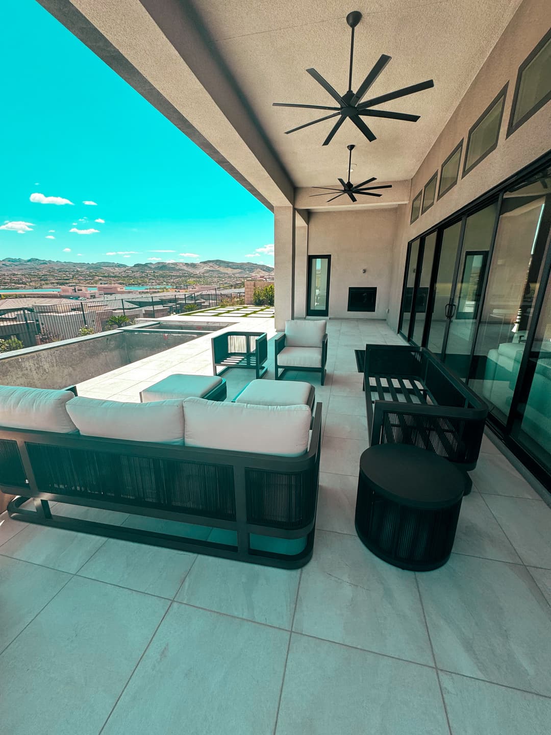 Modern outdoor patio with stylish seating, fans, and scenic mountain views.