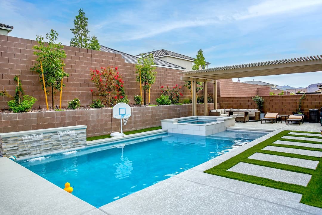 Backyard oasis featuring a pool, spa, landscaping, and basketball hoop. Perfect for relaxation.