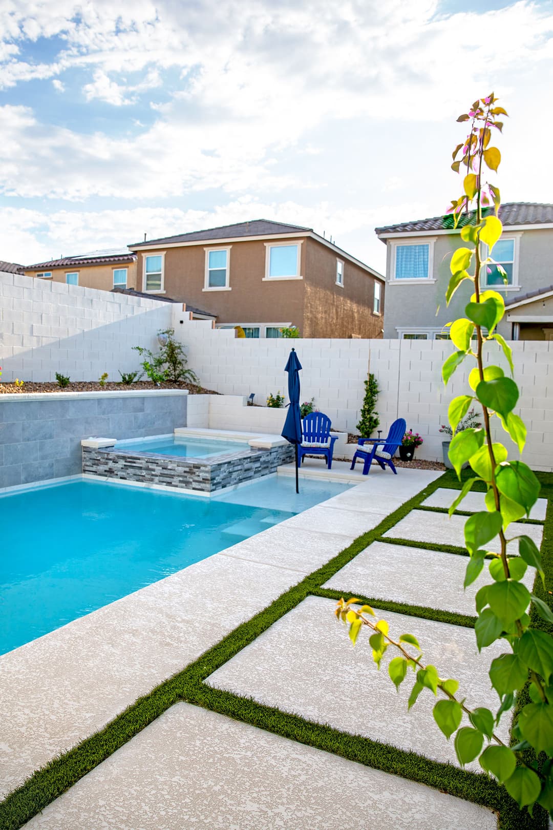 Beautiful modern backyard with a pool, spa, and landscaping in a residential setting.