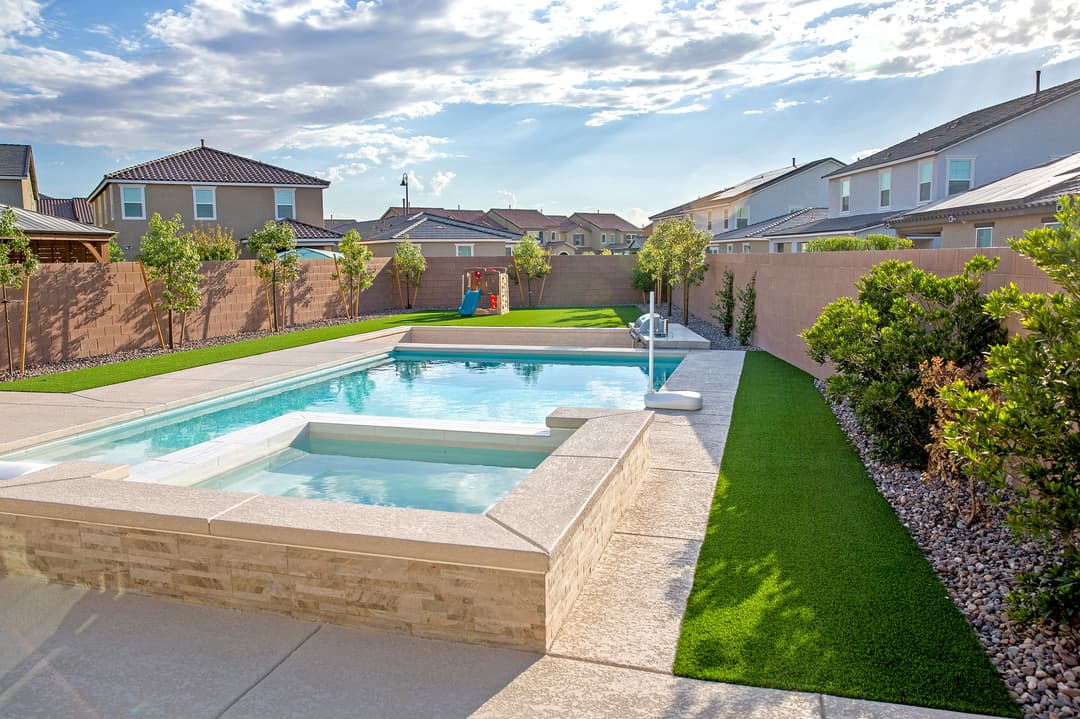 Modern backyard with a pool, landscaped garden, and clear blue sky. Ideal for outdoor relaxation.