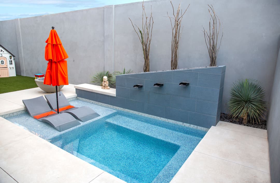 Modern backyard spa with a sleek design, orange umbrella, and relaxing water features.
